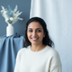 Smiling South Asian woman in her late 20s looking at the camera.