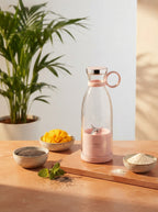 A portable mini blender on a terracotta surface with mango chunks and seeds in a sunlit, modern kitchen setting.